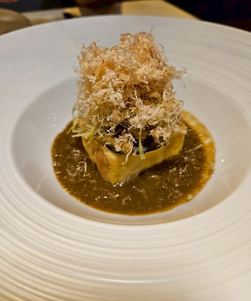 Homemade tofu plated with foie gras sauce and shiitake