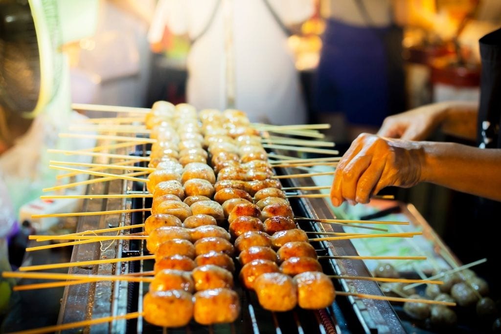 Grilled Sai Krok Isan sausages sizzling over charcoal grill
