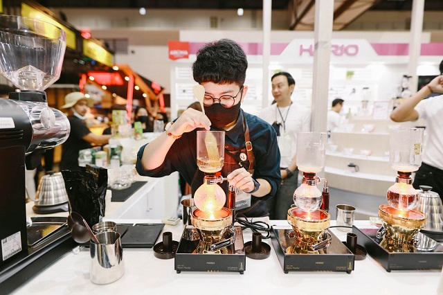 Female barista brewing coffee on induction burner at Thailand Coffee Fest 2025 in Bangkok