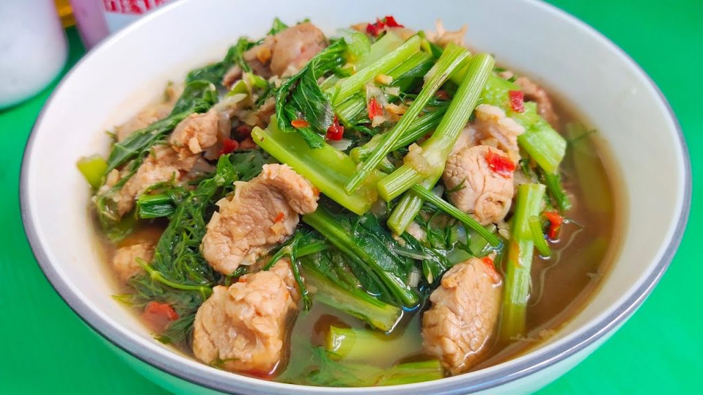 Bowl of clear herbaceous Gaeng Om curry with pork and fresh herbs