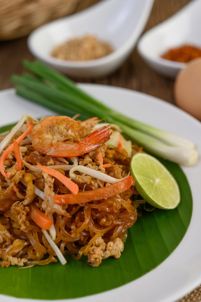 Pad Thai with shrimp, lime, and peanuts served on a white plate